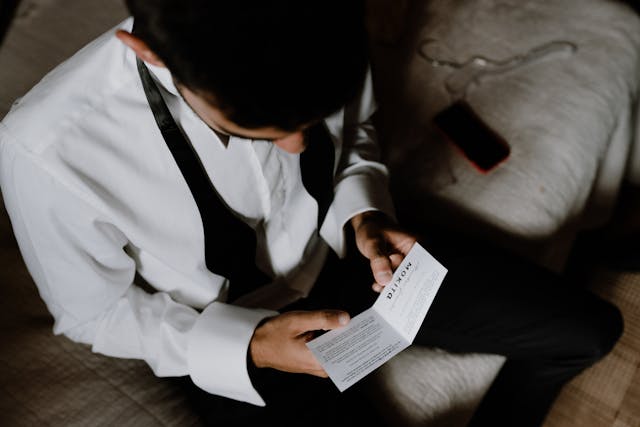 The groom reading a love letter sitting on the bed before their wedding